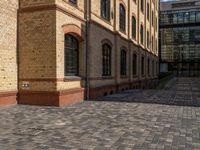 a sidewalk with chairs next to the brick building on the side, some have stairs and some buildings in the background