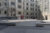 concrete benches are sitting in a courtyard surrounded by tall buildings on either side of the building, some of which are facing the ground