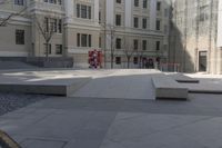 concrete benches are sitting in a courtyard surrounded by tall buildings on either side of the building, some of which are facing the ground