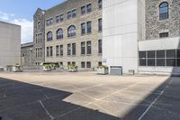 an outdoor courtyard with several different tables in the middle of it and several tall buildings with stone windows