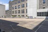 an outdoor courtyard with several different tables in the middle of it and several tall buildings with stone windows