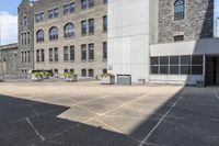 an outdoor courtyard with several different tables in the middle of it and several tall buildings with stone windows