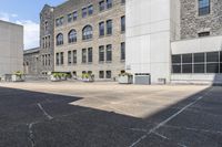 an outdoor courtyard with several different tables in the middle of it and several tall buildings with stone windows