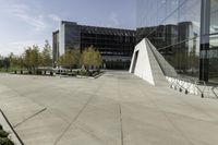 an urban courtyard with various benches and trees near a building under a clear sky with some buildings in the background