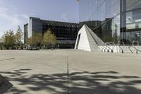 an urban courtyard with various benches and trees near a building under a clear sky with some buildings in the background