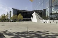 an urban courtyard with various benches and trees near a building under a clear sky with some buildings in the background