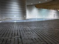 a light shines in a stone courtyard area and creates a reflection on the floor