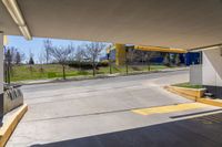 a view from under the overpass, looking towards an outside building with parking garages on both sides