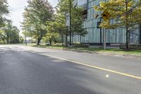 a person riding a bicycle down a road near trees and buildings on either side of the street