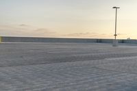 a man holding an umbrella over a parking lot with lots of empty spaces on each side