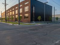 an empty street in front of a large red brick building on the other side of the road is a street light that has a line for motorists