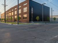 an empty street in front of a large red brick building on the other side of the road is a street light that has a line for motorists