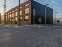 an empty street in front of a large red brick building on the other side of the road is a street light that has a line for motorists