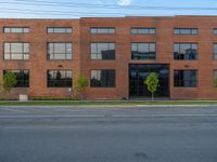 an empty street in front of a large red brick building on the other side of the road is a street light that has a line for motorists