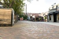 brick pavement in the center of town with small wooden planters on each side and tables set up at either end