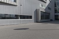 the young man skateboards on the paved parking space outside a large building on a sunny day