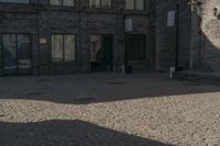 the person is walking down the street near old buildings on a sunny day with a red umbrella