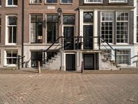 stairs and railings leading to three buildings on an empty sidewalk in the city of amsterdam, netherlands