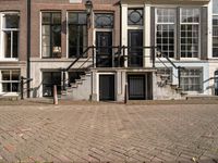 stairs and railings leading to three buildings on an empty sidewalk in the city of amsterdam, netherlands