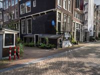 two tall brick buildings along a street with no parking spaces for cars and people outside