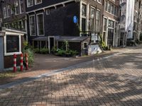 two tall brick buildings along a street with no parking spaces for cars and people outside