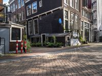 two tall brick buildings along a street with no parking spaces for cars and people outside