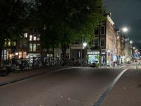 a city street with bikes and some lights in the distance next to buildings at night