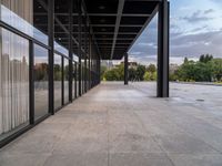 the large concrete area has large windows on each side and large metal pillars in the middle