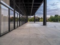 the large concrete area has large windows on each side and large metal pillars in the middle