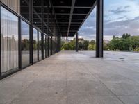 the large concrete area has large windows on each side and large metal pillars in the middle