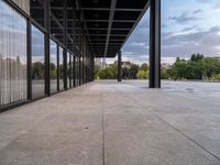 the large concrete area has large windows on each side and large metal pillars in the middle