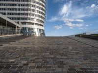 a walkway up to the top of a building on the beach with people and buildings in the background