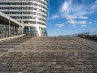 a walkway up to the top of a building on the beach with people and buildings in the background