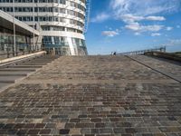 a walkway up to the top of a building on the beach with people and buildings in the background