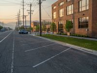 an empty street in front of a large red brick building on the other side of the road is a street light that has a line for motorists