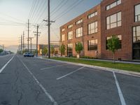 an empty street in front of a large red brick building on the other side of the road is a street light that has a line for motorists