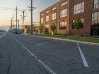 an empty street in front of a large red brick building on the other side of the road is a street light that has a line for motorists