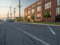 an empty street in front of a large red brick building on the other side of the road is a street light that has a line for motorists