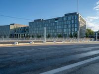 the empty street in front of the large building is not busy with cars around it