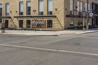 an empty street in front of a brick building with stairs and signage for dynamite pizza