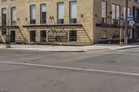 an empty street in front of a brick building with stairs and signage for dynamite pizza