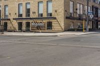 an empty street in front of a brick building with stairs and signage for dynamite pizza