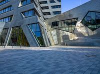 a person walking near a building with large windows and a concrete block floor in the middle