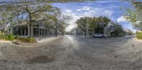 the view from a fish eye lens into an empty road with some trees and a truck