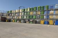 stacks of large containers are on a large racked area by a fence and street light