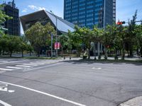 street intersection with a traffic light, trees and an airport building in the background on a sunny day