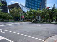 street intersection with a traffic light, trees and an airport building in the background on a sunny day