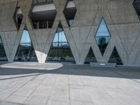 the floor is made out of concrete with many windows and a few people walking underneath it