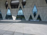 the floor is made out of concrete with many windows and a few people walking underneath it