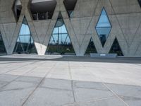 the floor is made out of concrete with many windows and a few people walking underneath it